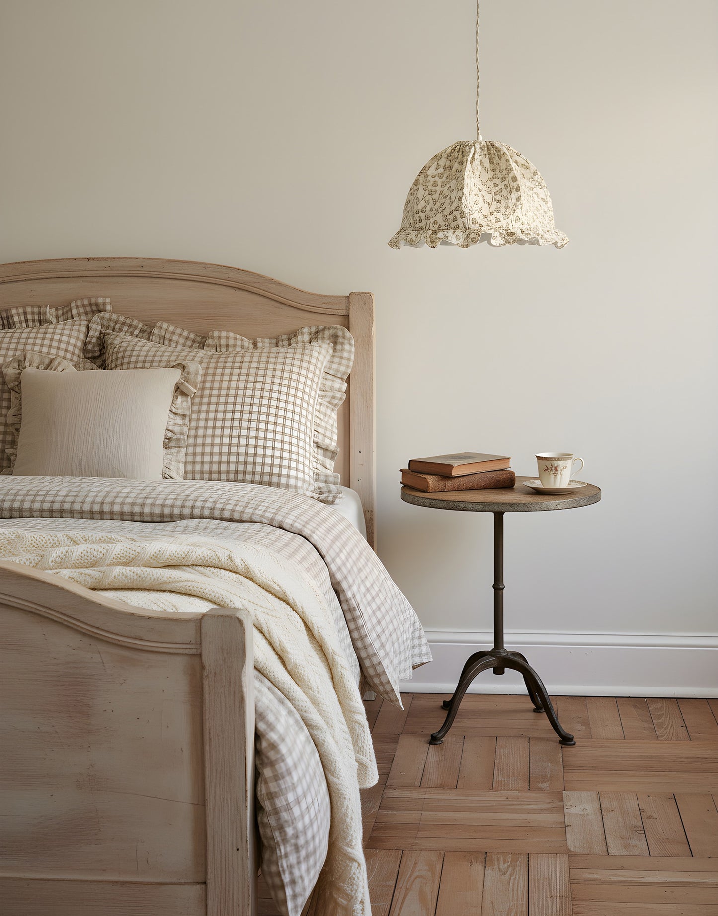 Suspension dôme arrondi imprimée de motifs brindilles au-dessus d'un lit en bois clair avec rideaux beige, et chevet en table ronde avec livres et tasse.